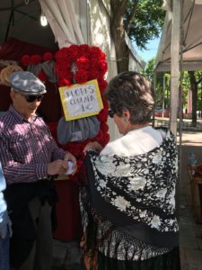 Una pareja de ancianos se coloca los claveles típicos en San Isidro