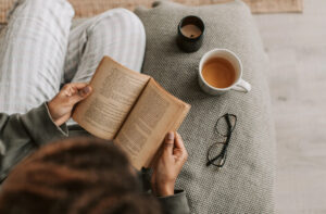 Lectora leyendo un libro mientras disfruta de una taza de café